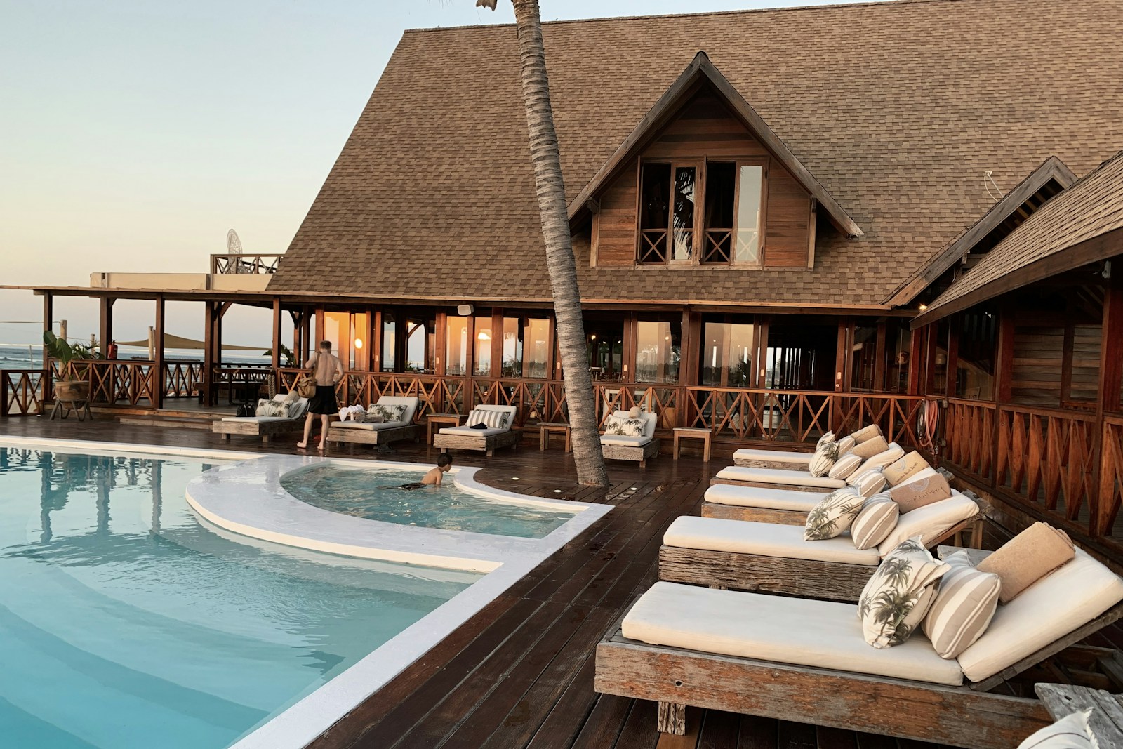 A timber resort beside a sunlit swimming pool